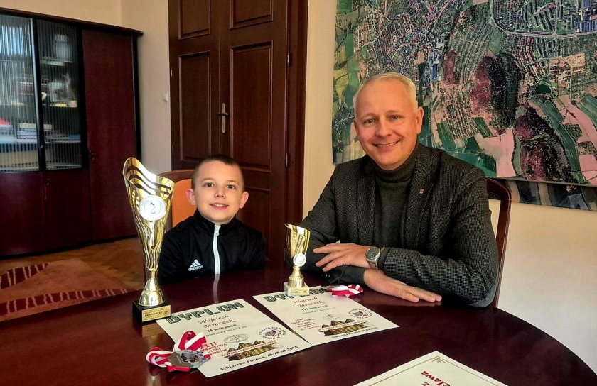 Wojciech z pucharami, medalami i dyplomami na spotkaniu u burmistrza